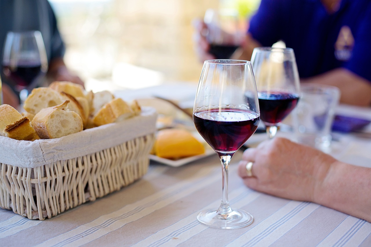 Photo of three people enjoying a picnic with red wine and a basket of bread