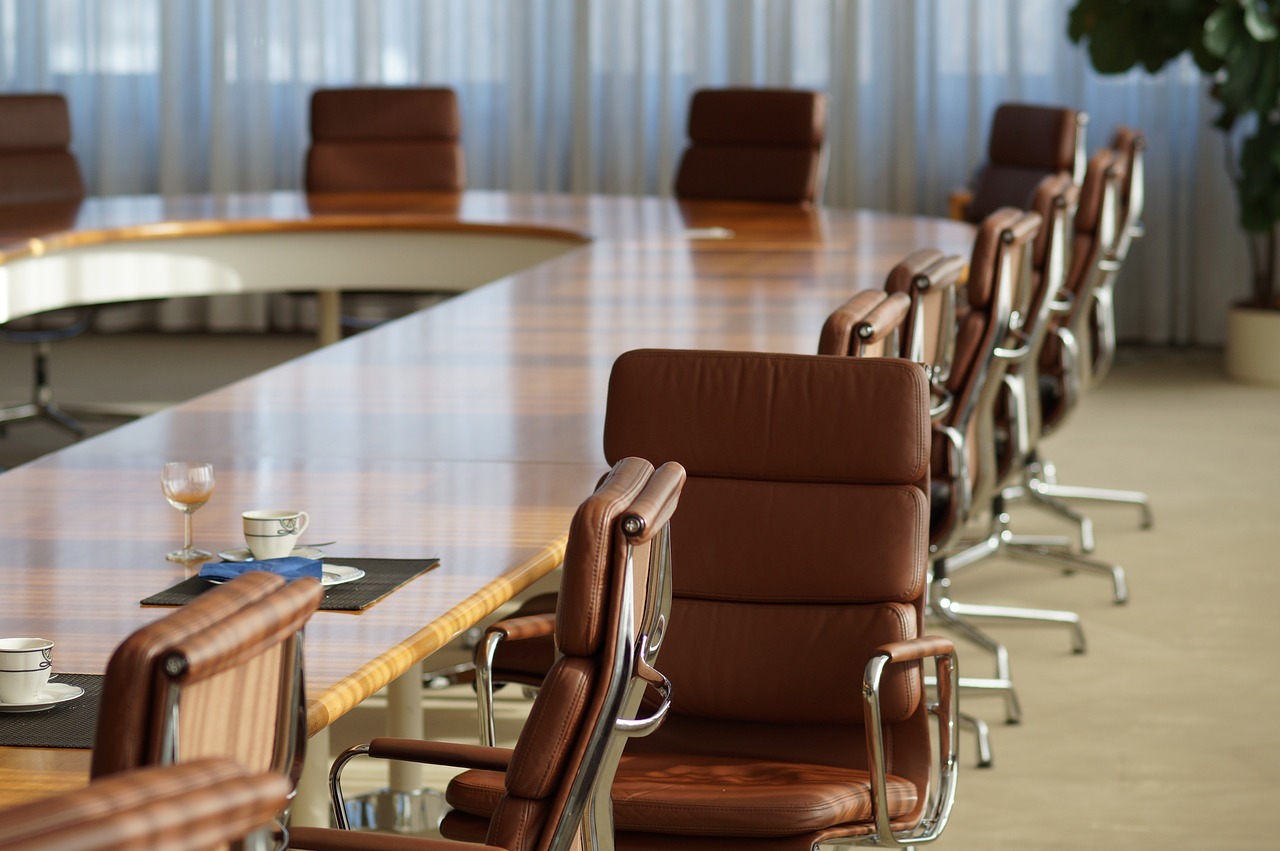 Photo of a conference room table with several empty brown leather chairs
